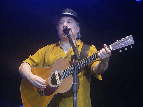 Paul Simon performing live with acoustic guitar